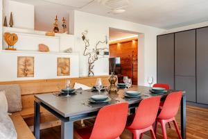カンポロッソ・イン・ヴァルカナレにあるHeritage Luxury Chalet 1 min from Mt Lussari Ski Liftのダイニングルーム(テーブル、赤い椅子付)