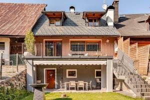 ein Haus mit einem Balkon und einem Tisch in der Unterkunft Heritage Luxury Chalet 1 min from Mt Lussari Ski Lift in Camporosso in Valcanale