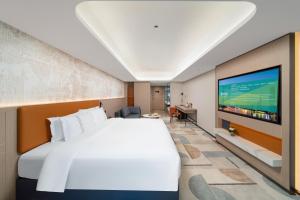 a hotel room with a large bed and a flat screen tv at Argyle Waifiden Hotel in Guangzhou