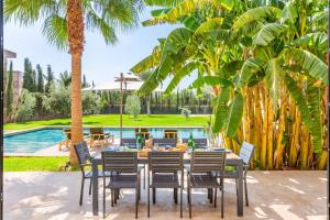 a dining table and chairs in front of a pool at Family villa in Marrakech in Marrakesh