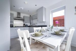 a white kitchen with a white table and chairs at 4-bedroom New House Near City Centre in Manchester