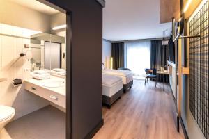 a hotel room with a bed and a bathroom at Radisson Hotel Düsseldorf City Center in Düsseldorf