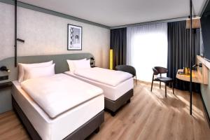 a hotel room with two beds and a desk at Radisson Hotel Düsseldorf City Center in Düsseldorf