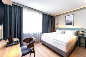 a hotel room with a bed and a chair at Radisson Hotel Düsseldorf City Center in Düsseldorf