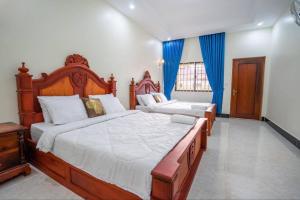 - 2 lits dans une chambre avec des rideaux bleus dans l'établissement Golden Angkor Guest House, à Phumĭ Trăm Néak