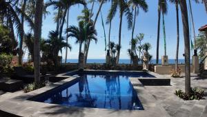 a swimming pool with palm trees and the ocean at jasriombak in Jasri