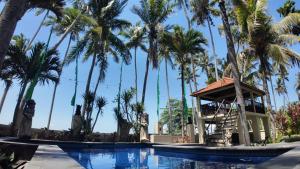 a swimming pool with palm trees and a gazebo at jasriombak in Jasri