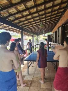 a group of people standing around ping pong tables at Casa Condado Maricá in Maricá