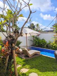 a garden with a chair and an umbrella next to a pool at Villa Nusa 8 in Ungasan