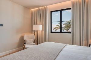 a bedroom with a bed and a chair and a window at Villa Mangoni - Brand New Luxury Villa in Funchal +42 photos