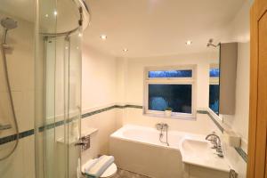 Un baño con bañera, lavabo y ducha. en Weybridge Stunning Five Bedroom House With Garden, en Oatlands Park