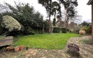 un patio trasero con un jardín con un banco y plantas en Weybridge Stunning Five Bedroom House With Garden, en Oatlands Park