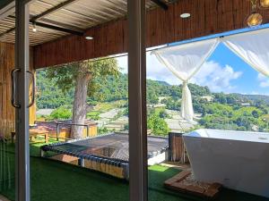a bathroom with a bath tub and a large window at ภูแสงไฟโฮมสเตย์ in Ban Tai
