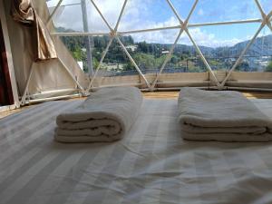 a room with a bed with two pillows and a window at ภูแสงไฟโฮมสเตย์ in Ban Tai