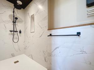 a bathroom with a shower with white marble walls at Emeraude vue mer MALO LES BAINS in Dunkerque +8 photos