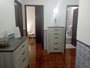 ein Schlafzimmer mit einer Kommode und ein Badezimmer mit einem Waschbecken in der Unterkunft As Irmãs in Reguengos de Monsaraz