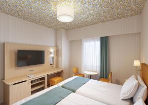 ein Hotelzimmer mit einem Bett und einem Flachbildfernseher in der Unterkunft Hotel Monterey La Soeur Naha in Naha