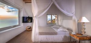 una camera da letto con letto a baldacchino e finestra di Villa Montessito Mykonos a Tourlos