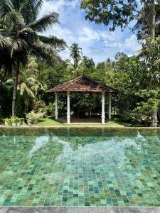 a swimming pool with a gazebo in a yard at Elephant Heritage Pinnawala by Moon Isle in Rambukkana