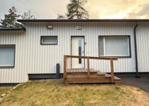 a house with a wooden deck in front of it at Valoisa uusi kaksio keskellä Suomea in Haapavesi