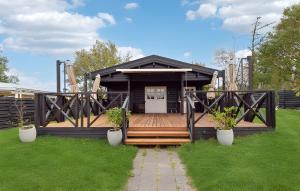 a black house with a wooden deck with two plants at Feriehus - Ramløse, Danmark in Helsinge