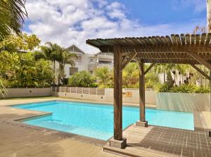 ein Swimmingpool mit Pergola neben einem Gebäude in der Unterkunft Appartement Club Ocean in L'Ermitage-Les-Bains