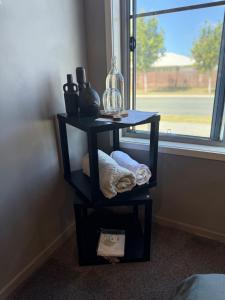 een zwart bijzettafeltje met een glazen vaas erop naast een raam bij The Atelier Artful Home Stay at Mangohill in North Lakes +86 foto's