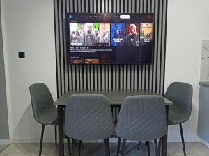 a dining room table with chairs and a tv on a wall at Domek pod lasem in Karmanowice