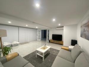 a living room with a couch and a tv at Bayview Luxury Waterfront Escape with Pool & Spa in Green Point