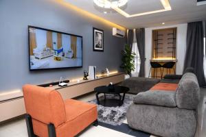 a living room with a couch and a tv on the wall at lusso Court in Agidingbi