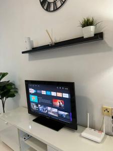 a flat screen tv sitting on a white desk with a clock at Eira Homestay Lost World Of Tambun M uslim only in Ipoh