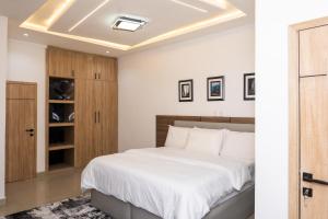 a bedroom with a large white bed and wooden cabinets at lusso Court in Agidingbi +35 photos