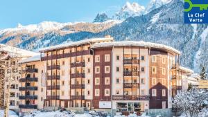 un hotel con montañas cubiertas de nieve en el fondo en Résidence Pierre & Vacances La Rivière, en Chamonix-Mont-Blanc