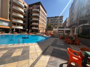 a swimming pool with tables and chairs and buildings at Hotel apartment in Monte Cairo Mokattam d202a in Cairo