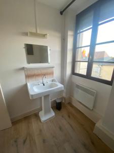 baño con lavabo blanco y ventana en Magnifique grand appartement dans le Morvan, en Château-Chinon