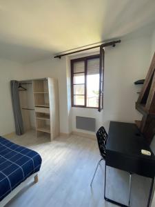 Una habitación con una cama y un escritorio y una ventana. en Magnifique grand appartement dans le Morvan, en Château-Chinon