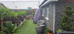 ein kleiner Hinterhof mit Gras, Stühlen und Pflanzen in der Unterkunft Cosy Studio Quest House in Romford