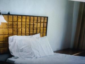 a bed with a white pillow and a wooden headboard at Hotel Haridwar in Bahādrābād