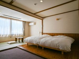 ein Schlafzimmer mit einem Bett in einem Zimmer mit Fenster in der Unterkunft Hotel Goryukan in Hakuba