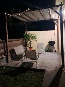 a group of chairs under a pergola with lights at Au coin de la cheminée in Saint-Leu