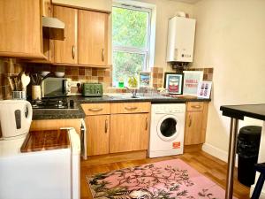 a kitchen with wooden cabinets and a washer and dryer at Peaceful park side apartment in Hastings