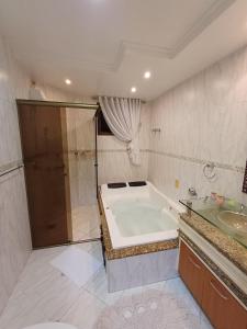 a bathroom with a bath tub and a sink at Casa no Centro de Pomerode - Pousada in Pomerode