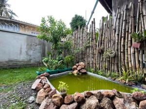a garden with a pond in front of a wooden fence at Homestay342 in Phumĭ Svay Chh'êh