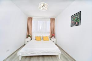 a white bedroom with a white bed and yellow pillows at Simple and Modern, apartament with rating 10 out of 10, WiFi, parking, air conditioning, free cancelation in Timişoara