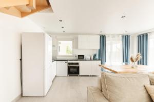 a kitchen with white cabinets and a wooden table at Villa Fantasia - 10 min Disneyland - 8 people in Coupvray