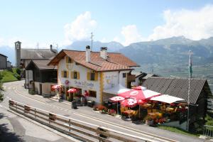 a building with tables and umbrellas on a road at B&B Café de la Poste in Agettes