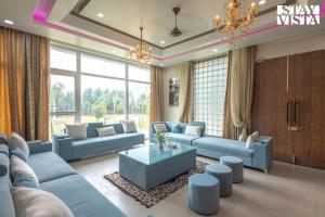 a living room with blue couches and a table at StayVista at Echoes by the Aravalli with Bonfire, Lawn in Jaipur