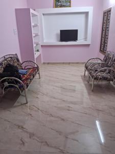 a room with two chairs and a tv on a wall at LAKSH COTT Home Stay in Arumuganeri
