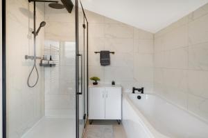 ベッドフォードにあるModern 5BR Bedford Home, Sleeps 7,Ideal for Contractors Stay, Near Transportの浴槽とシャワー付きの白いバスルーム