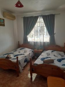 two twin beds in a room with a window at Maison proche de toutes commodités in Port Louis +12 photos